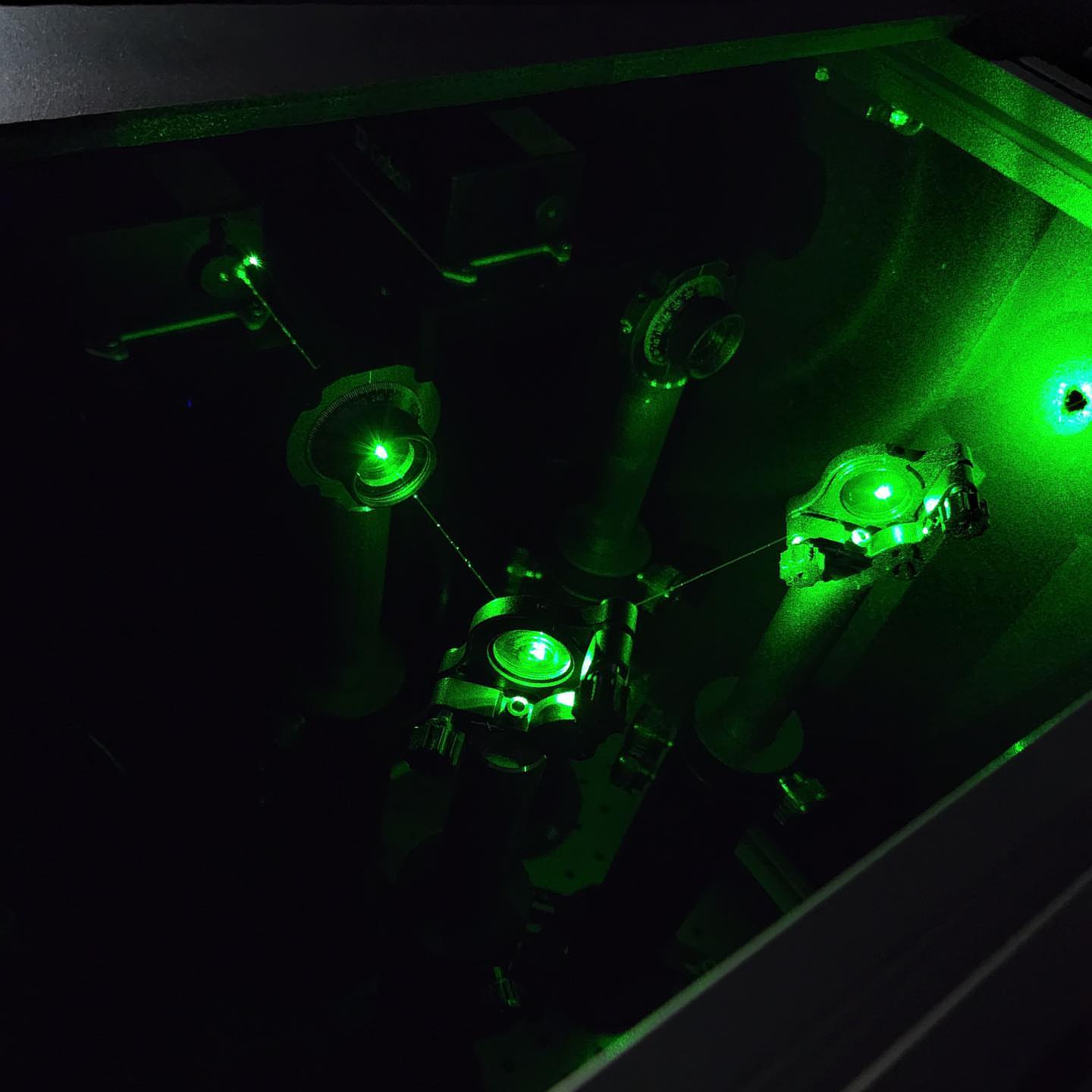 Beam-splitting optics glowing green in darkness