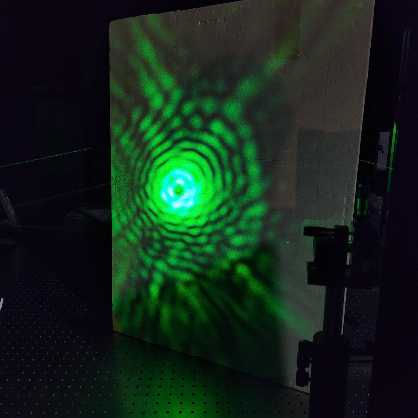 Interference ring pattern of expanded green laser light on a white board