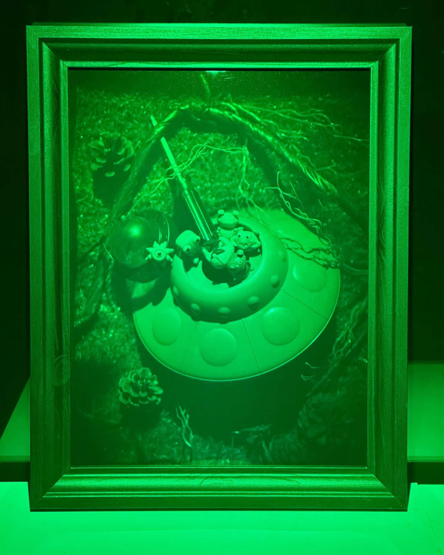 Green framed hologram of a toy flying saucer in grass