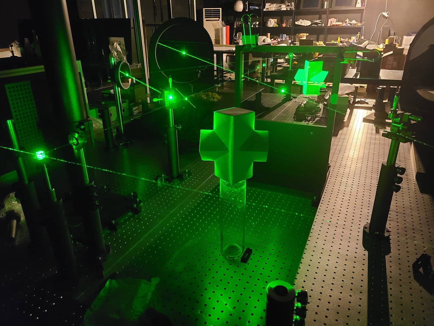 Laser beams crossing an optical table with mirrors and mounts in the dark studio